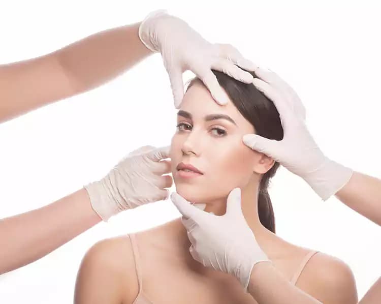 Gloved hands assessing a patient's facial skin